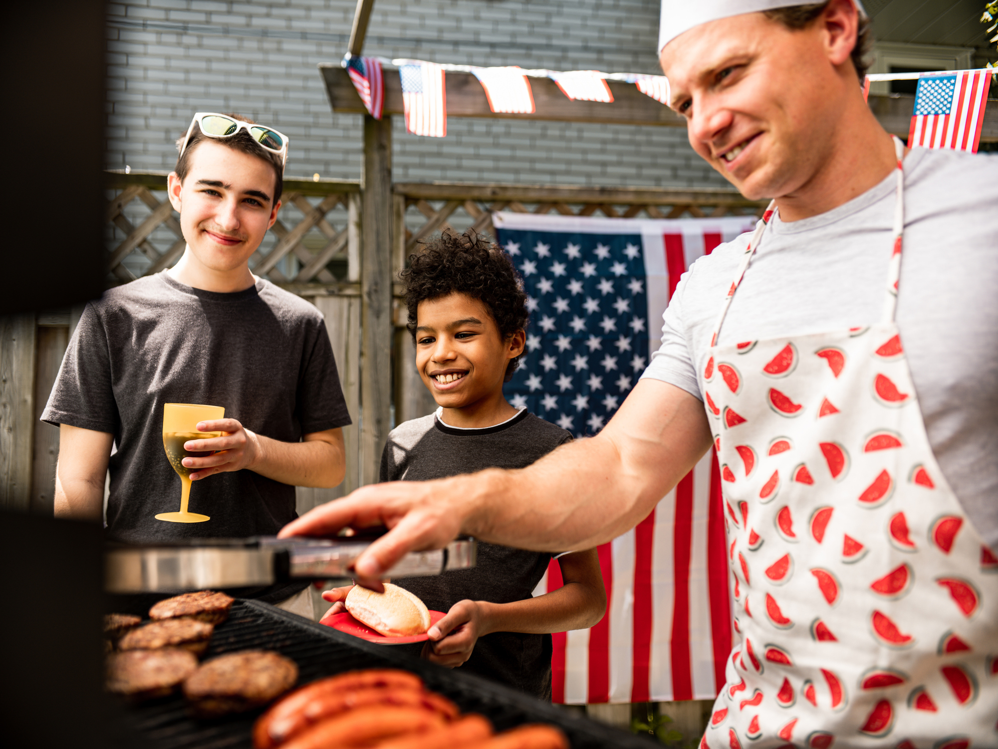 Grilling burgers at the BBQ grill for outdoor backyard celebration.